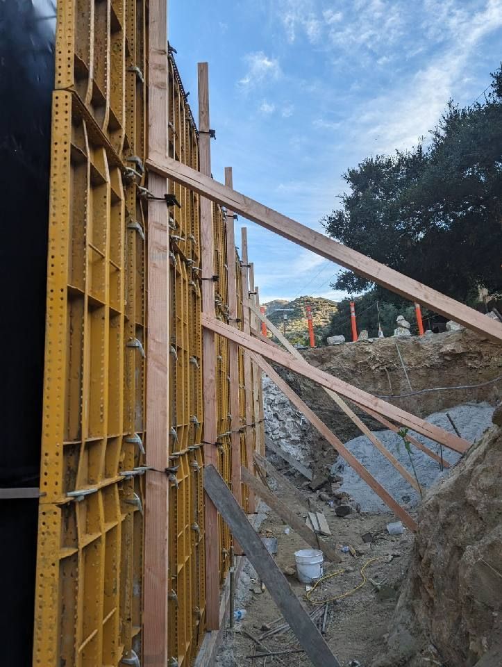 A wooden wall is being built on a dirt road