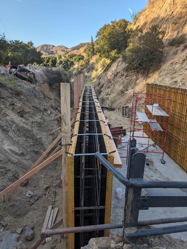 A large concrete wall is being built in a canyon.