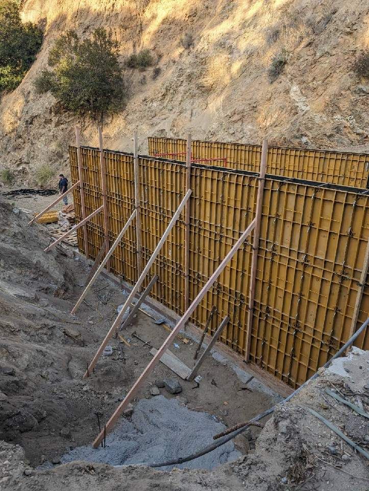 A concrete wall is being built on the side of a hill.