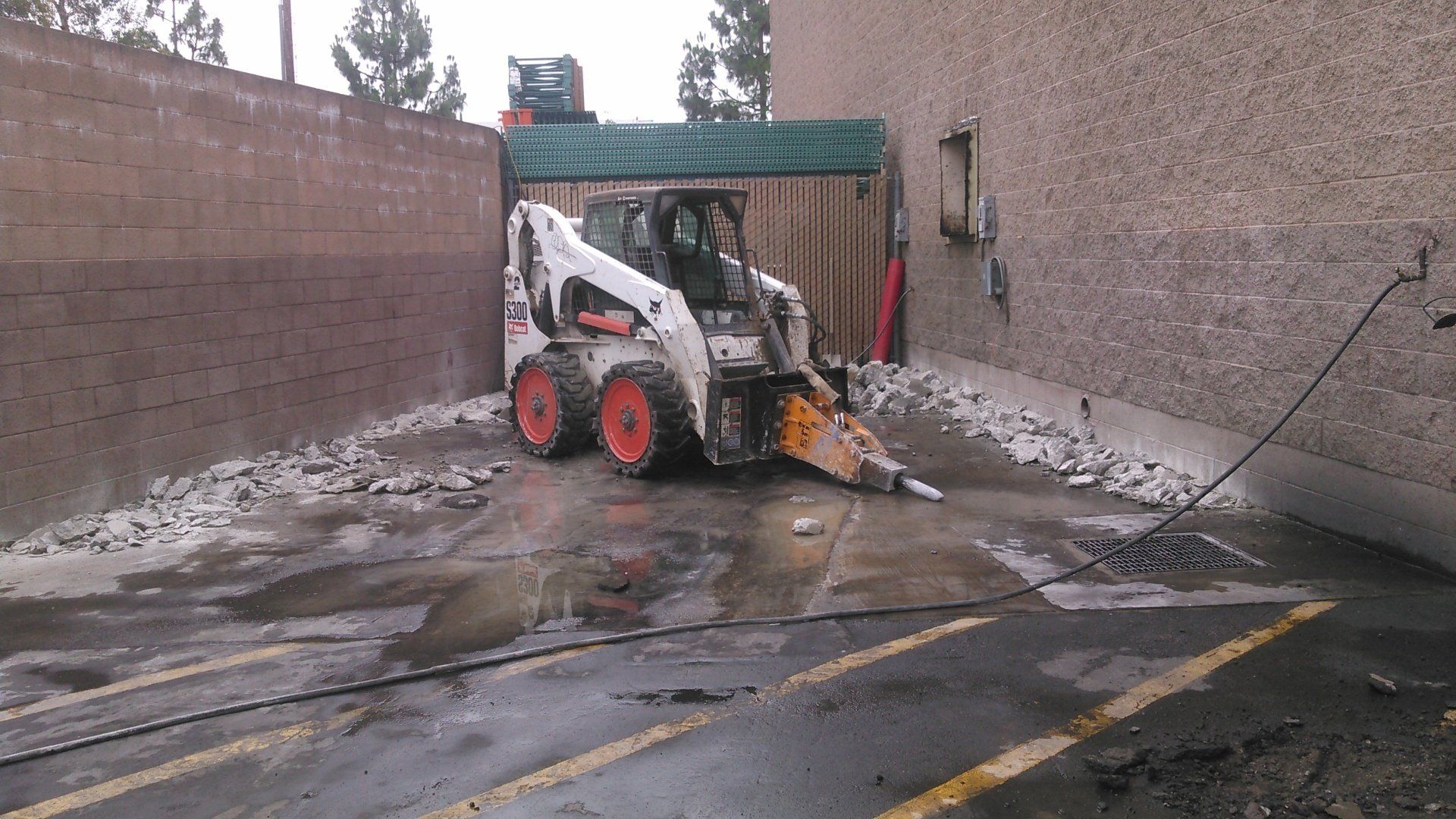 A bobcat is parked in a parking lot in front of a building.