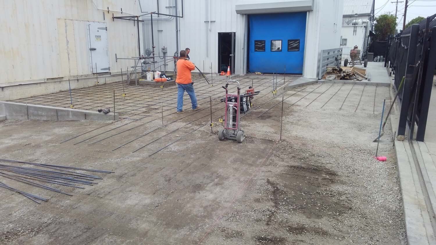 A man is standing in the dirt in front of a building with a blue garage door.