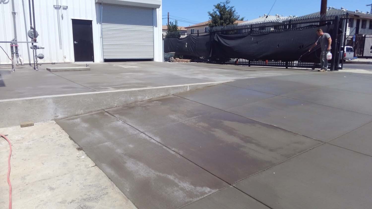 A man is working on a concrete driveway in front of a building.