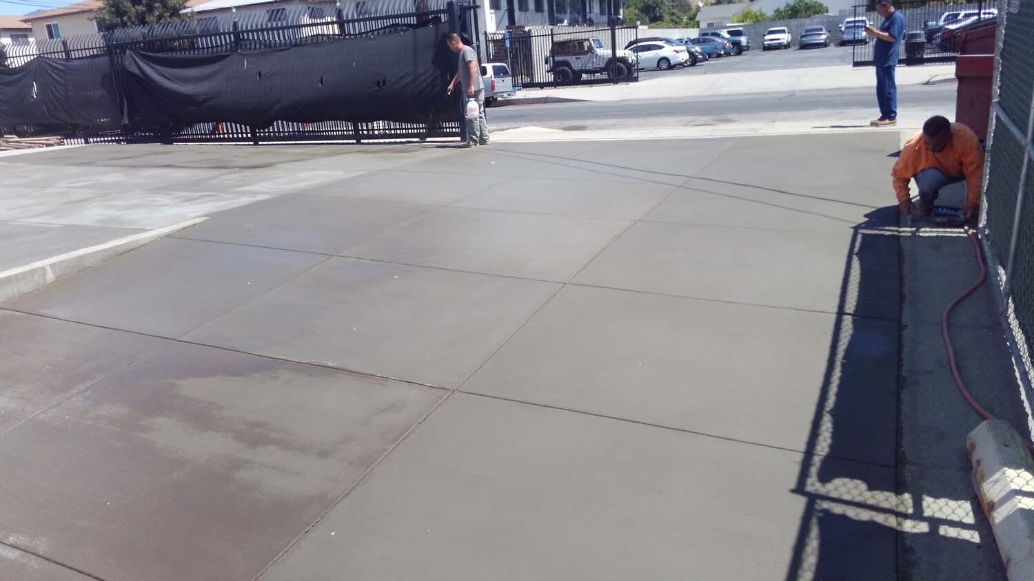 A man is working on a concrete driveway in a parking lot.
