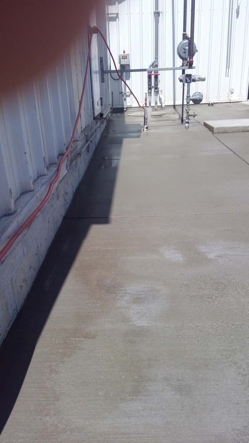 A concrete floor with a hose attached to it and a white building in the background.