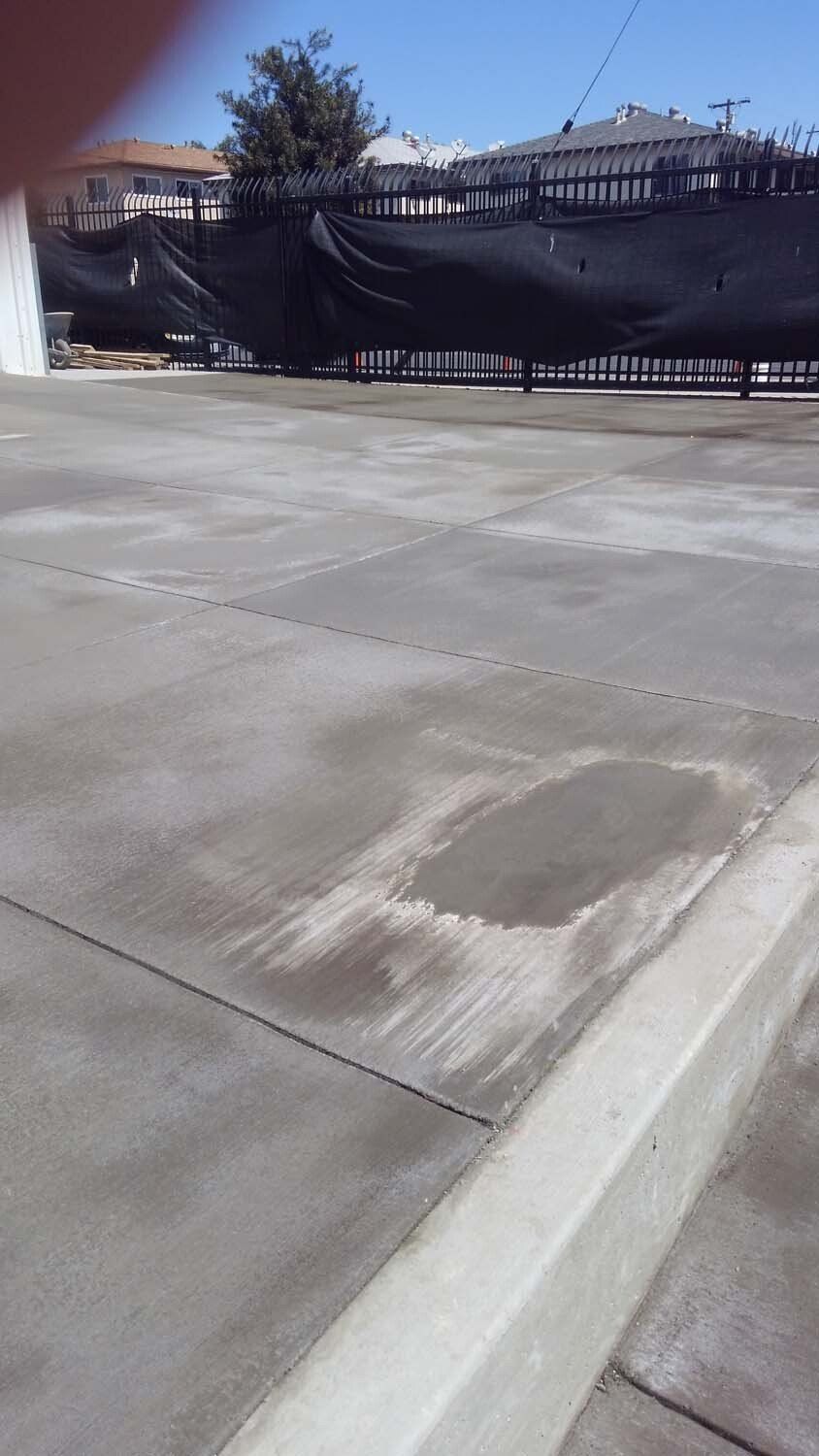 A concrete driveway with a black fence in the background.