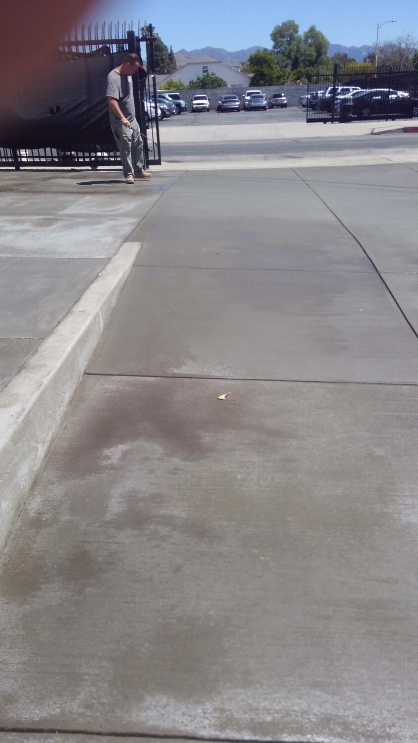 A man is standing on a sidewalk in a parking lot