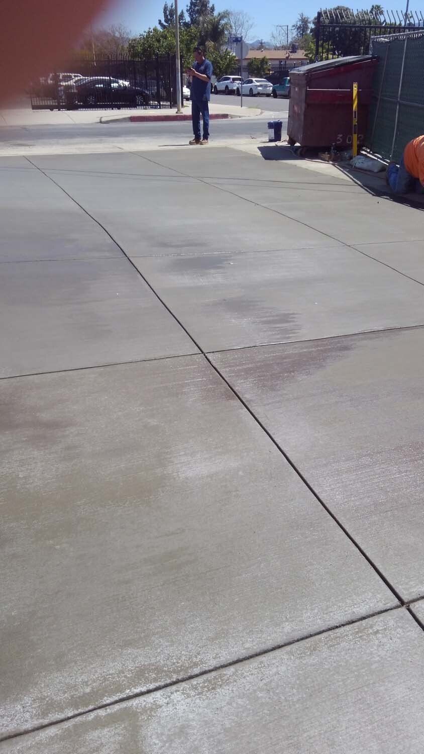 A man is standing on a concrete sidewalk in a parking lot.