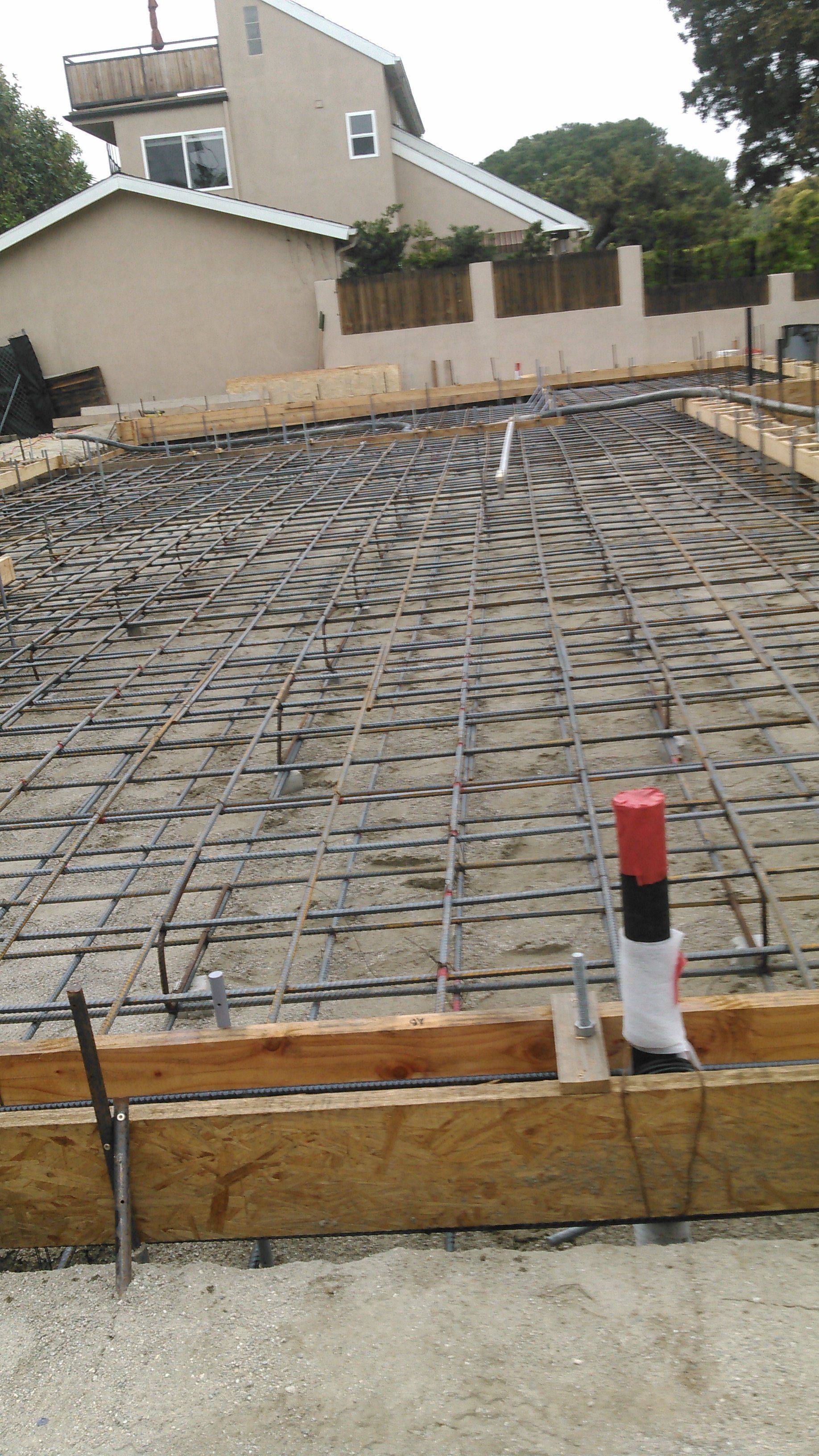 A concrete foundation is being built in front of a house