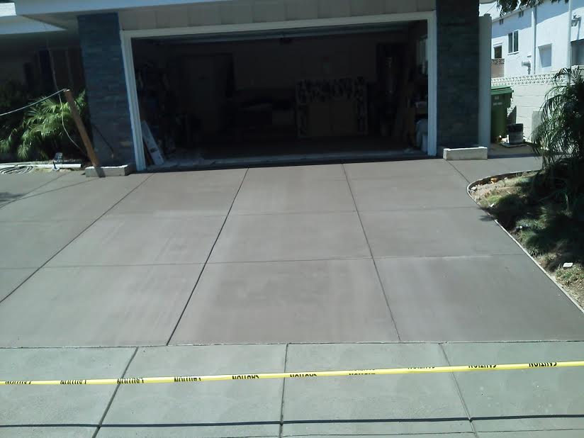 A concrete driveway with a garage in the background