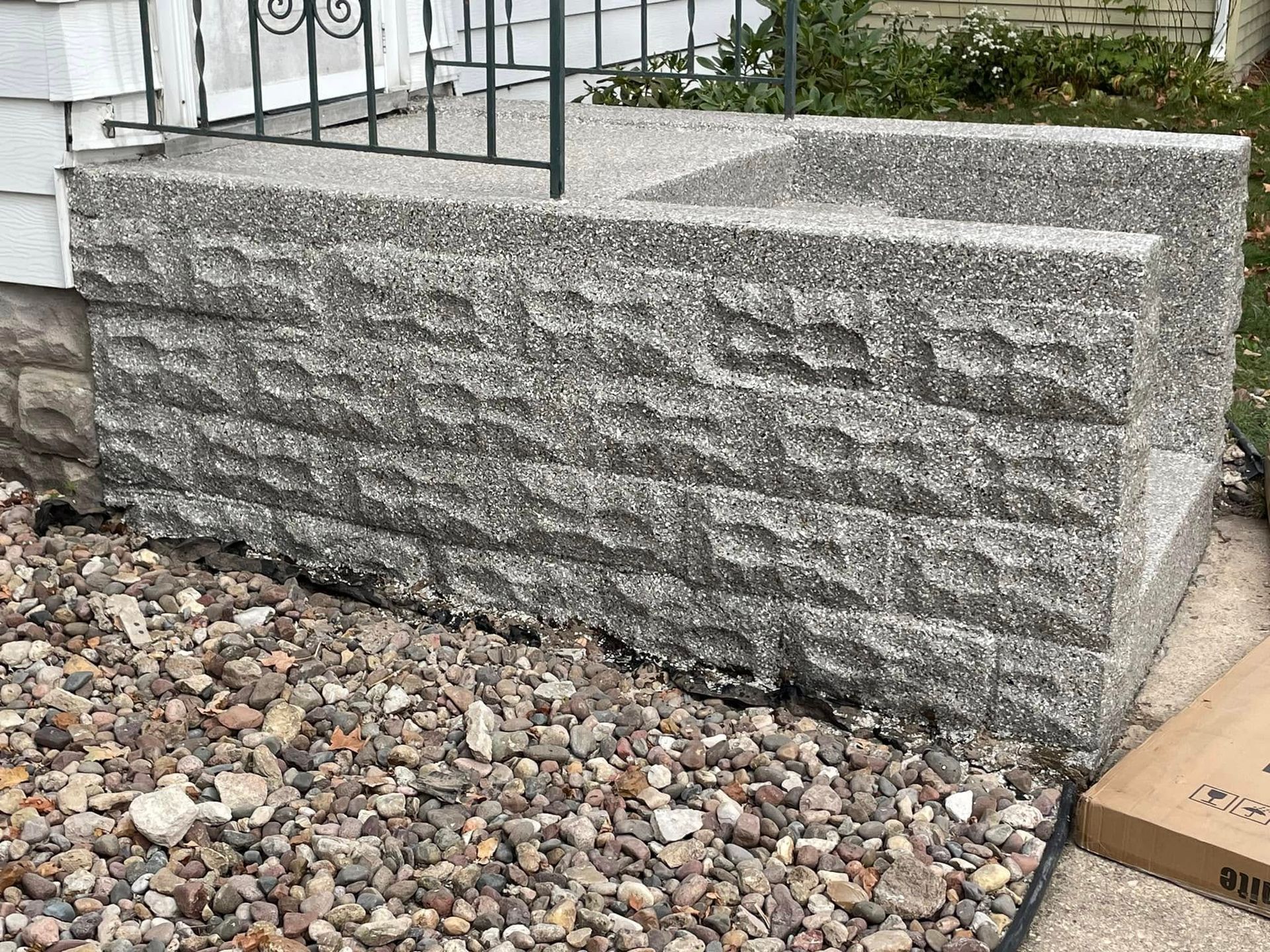 Gray textured concrete front steps with brick pattern and gravel base.