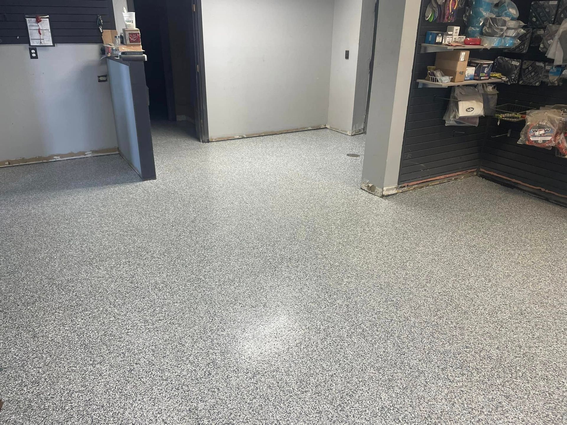 Gray speckled epoxy floor in a retail space, near shelves and doorway.