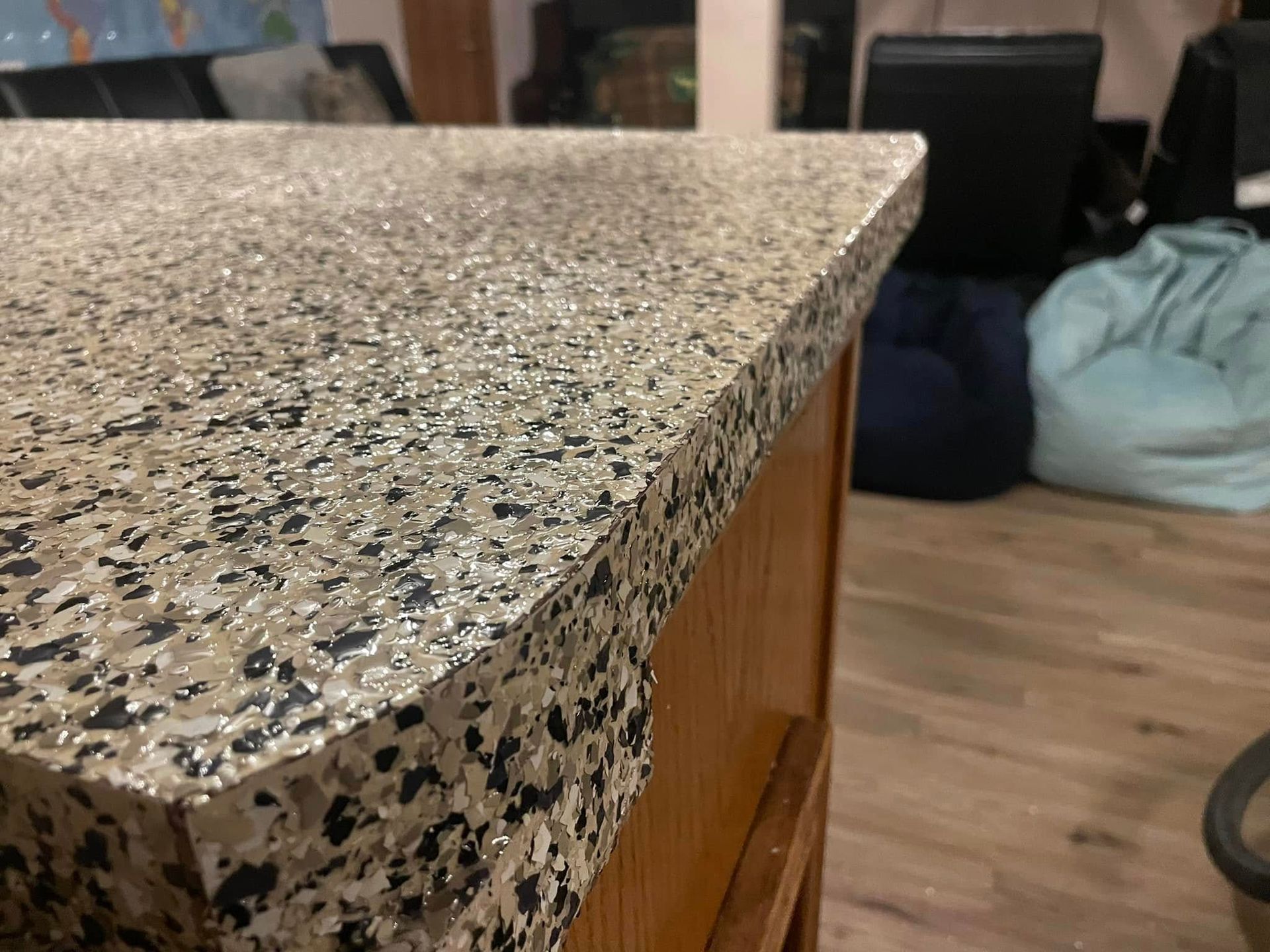 Close-up of a countertop with a speckled, light brown and black pattern, sitting on wooden cabinets.