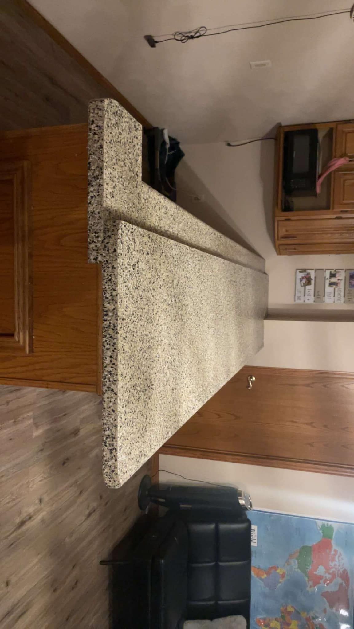 Kitchen counter with speckled countertop and wooden cabinets.