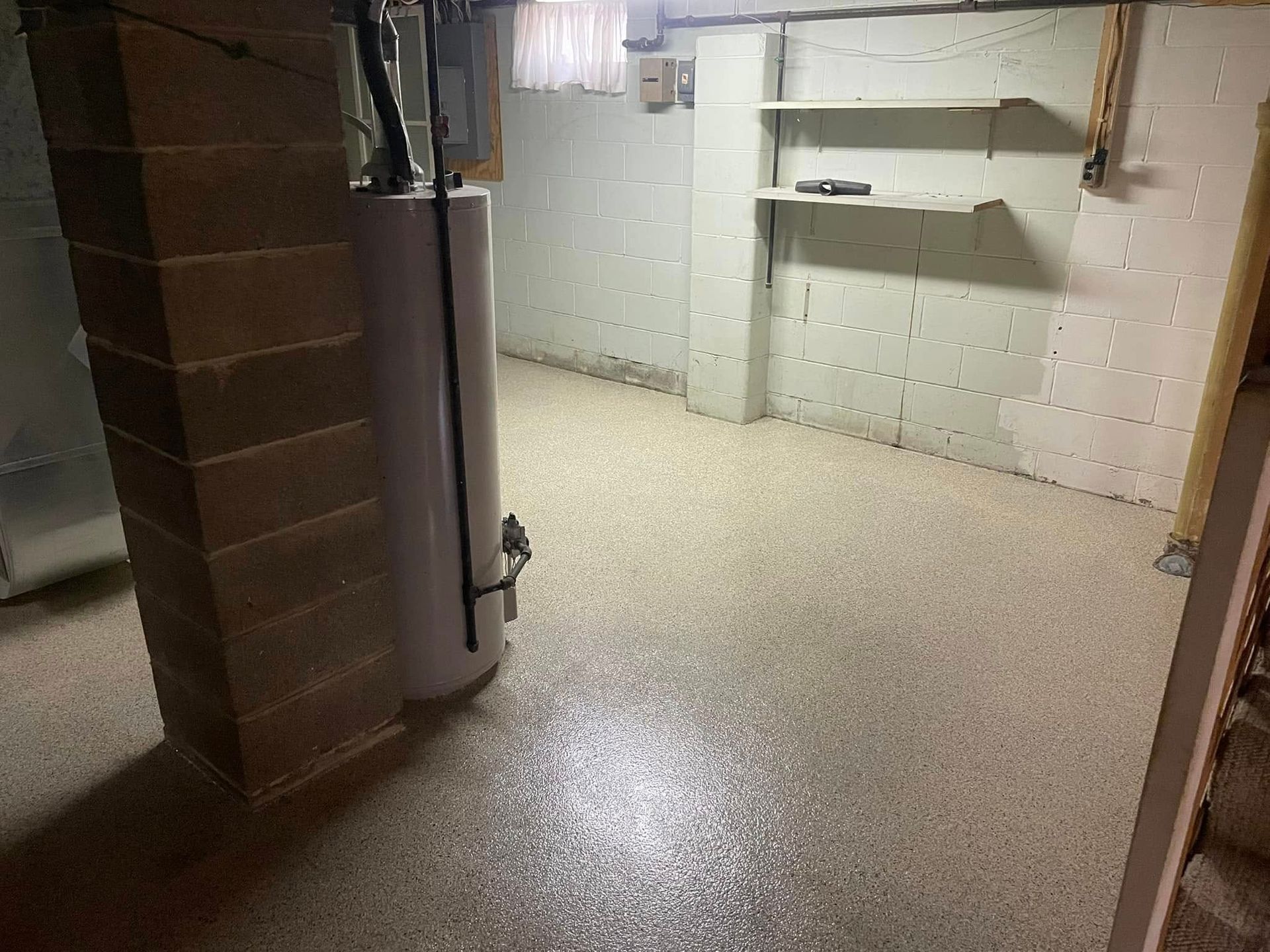 Basement with water heater, concrete block walls, shelving, and speckled epoxy floor.