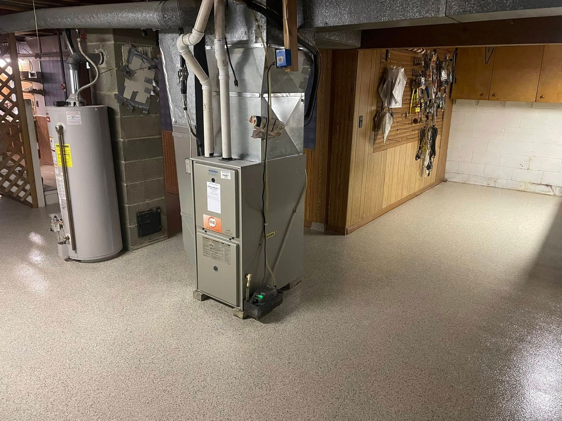 Basement interior with water heater, furnace, ductwork, and speckled epoxy floor.