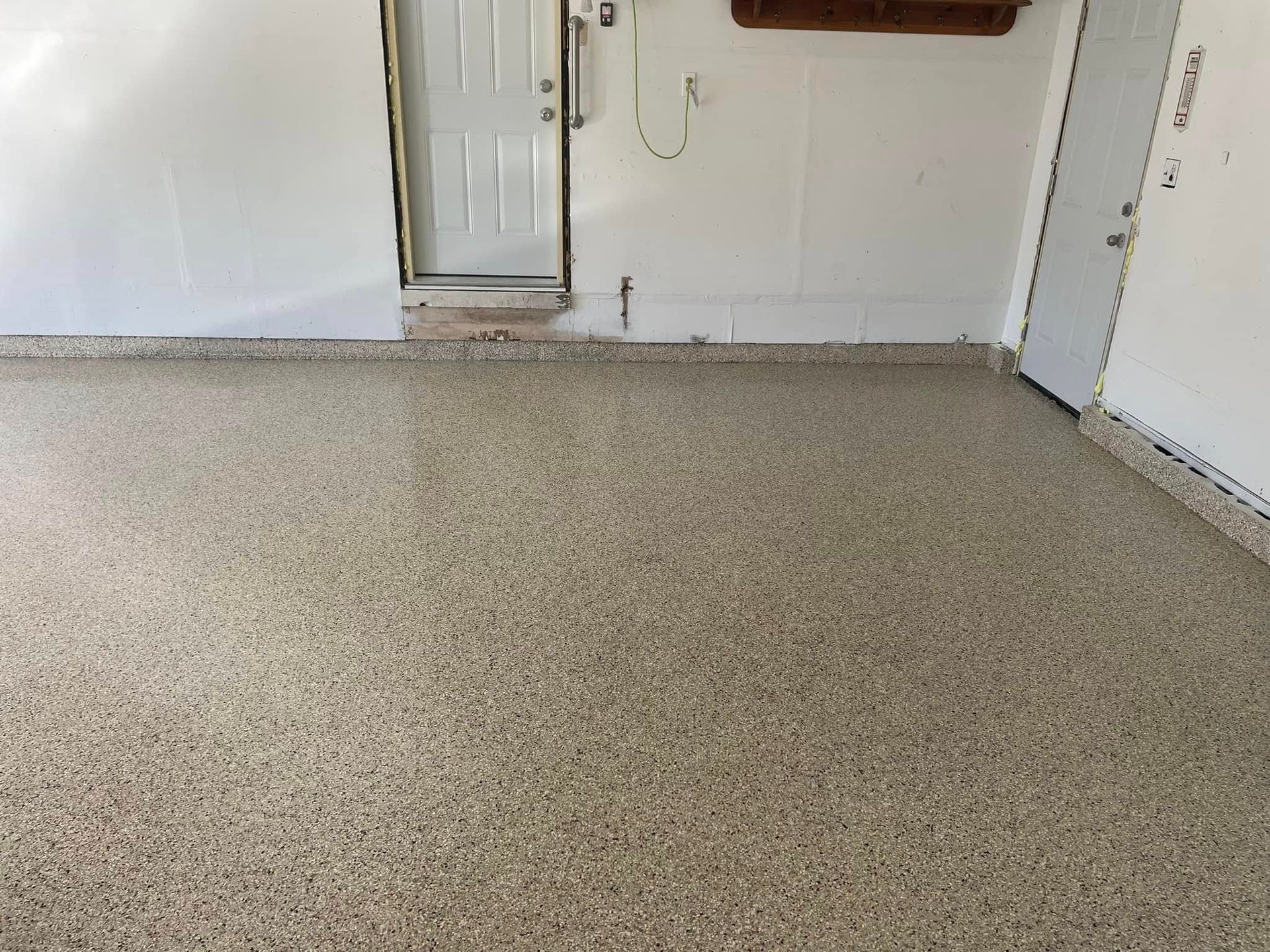 Garage with speckled epoxy floor, white walls, and two doors.