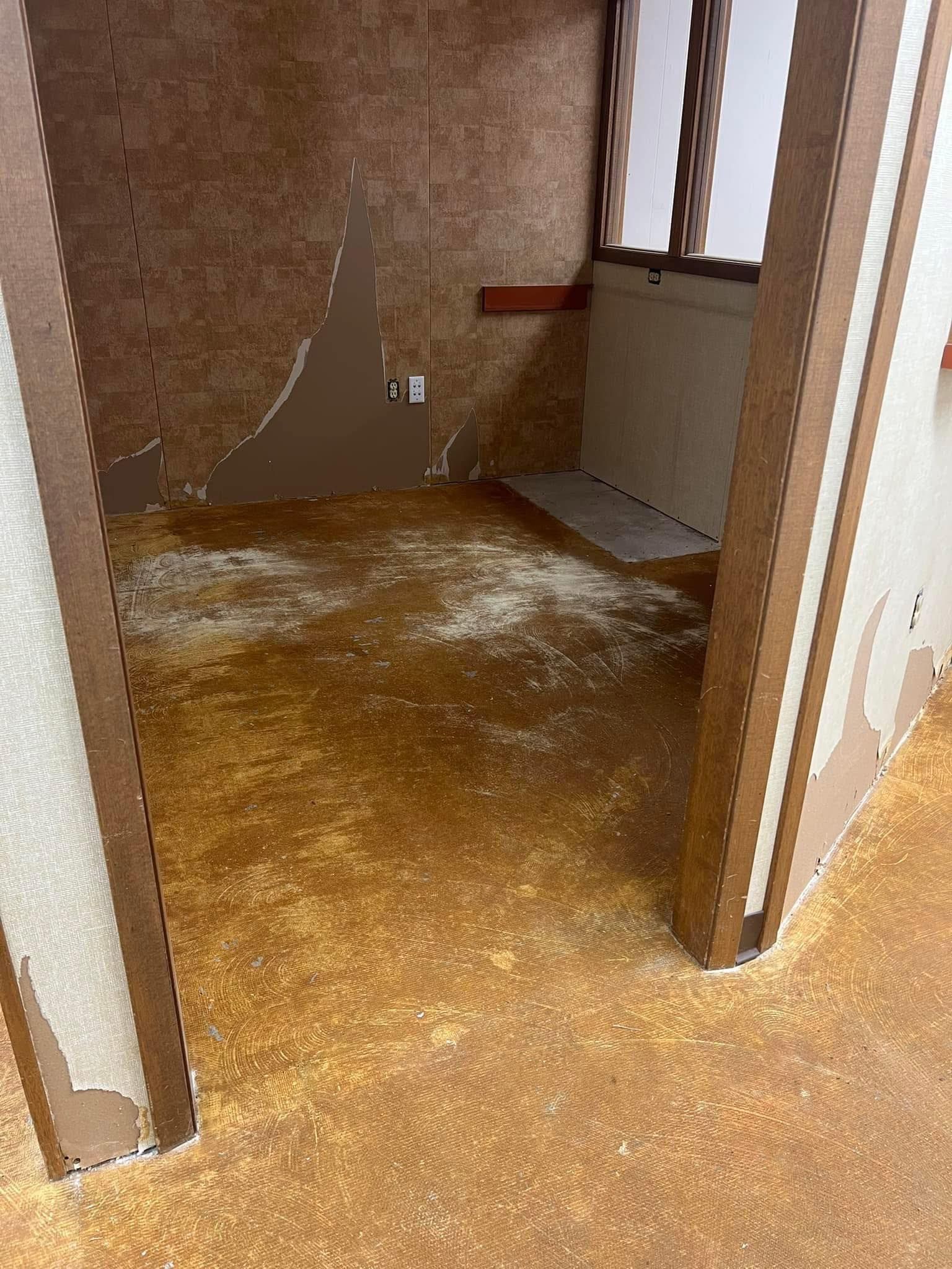 Empty room with peeling brown walls and floor, possibly water damage.