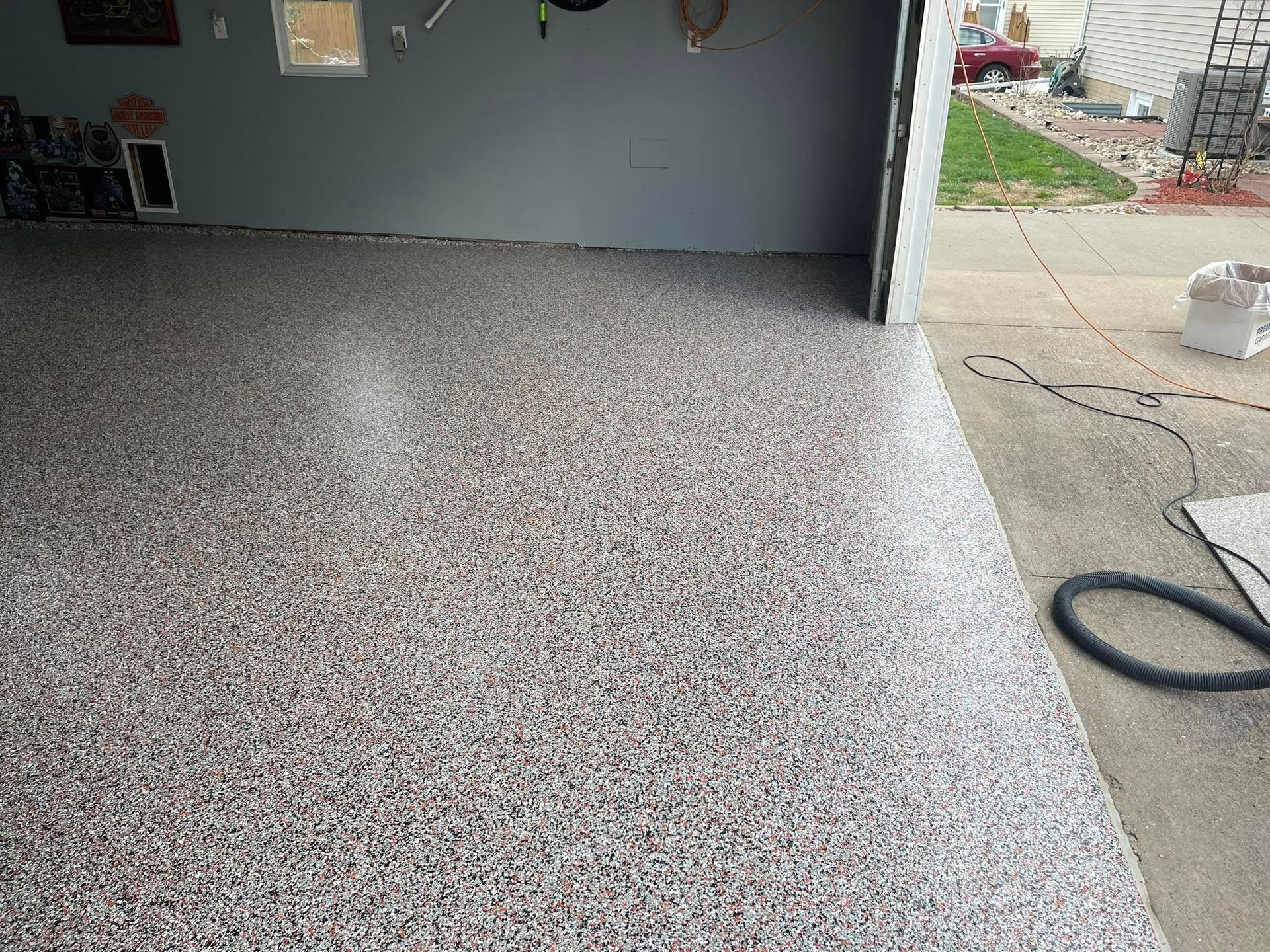 Garage with epoxy-coated floor in shades of gray, white, and brown; garage door open.