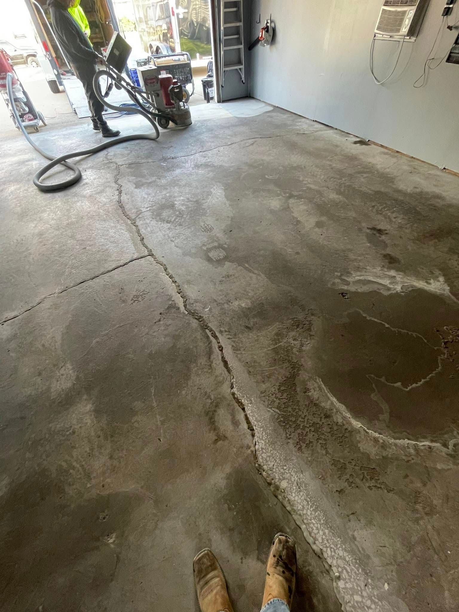 Cracked concrete floor in a garage with a person operating machinery.