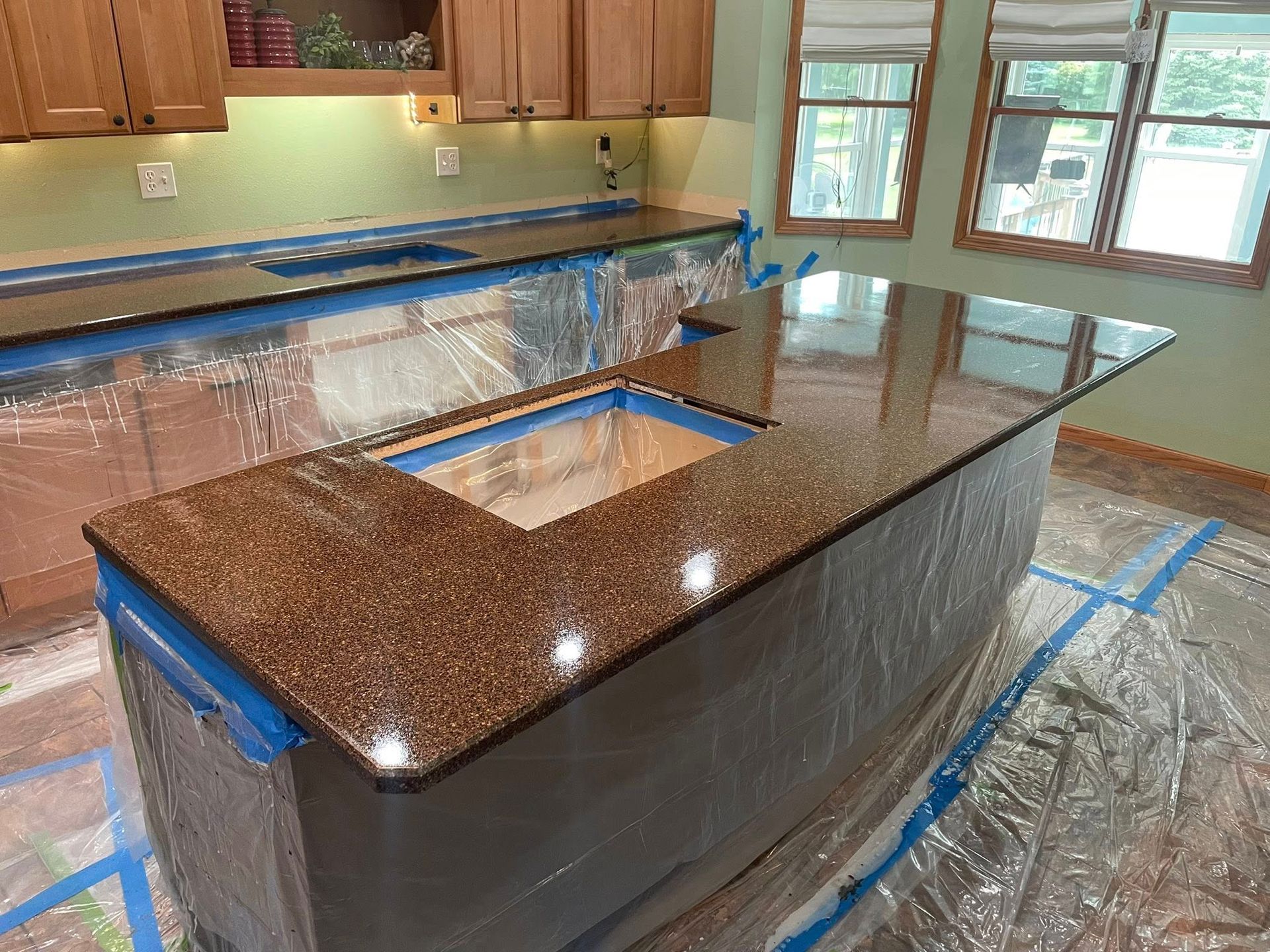 Granite countertops installed on a kitchen island and counter, covered in plastic, preparing for installation.