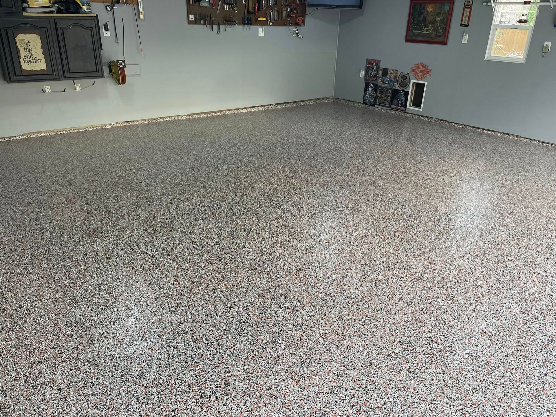 Garage with epoxy-coated floor, speckled with gray and brown chips. Gray walls and trim.