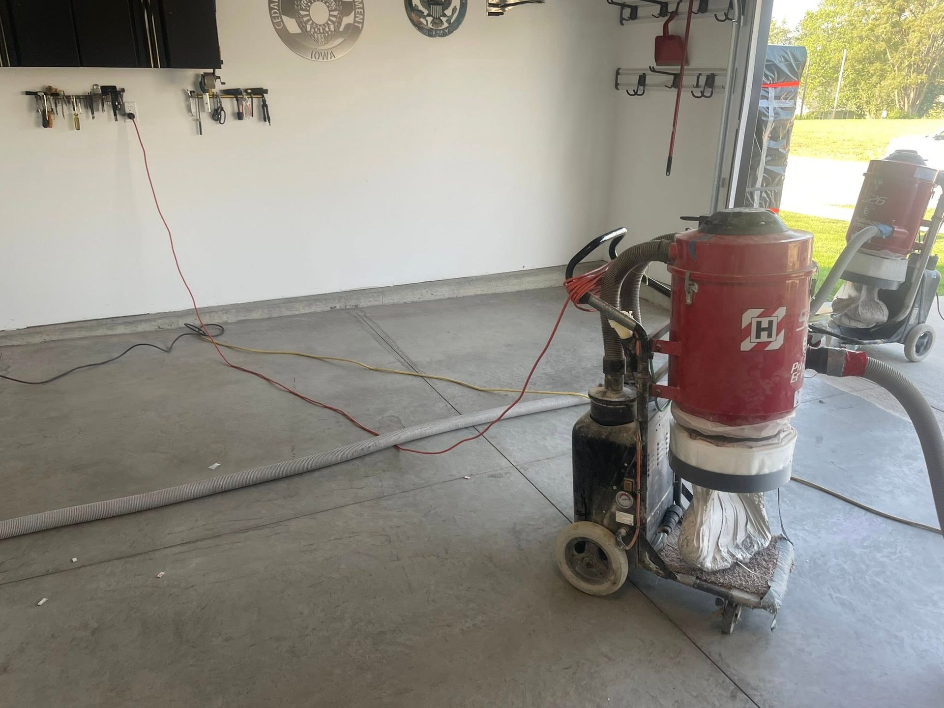 Concrete grinding machine in a garage, connected to a vacuum and power.