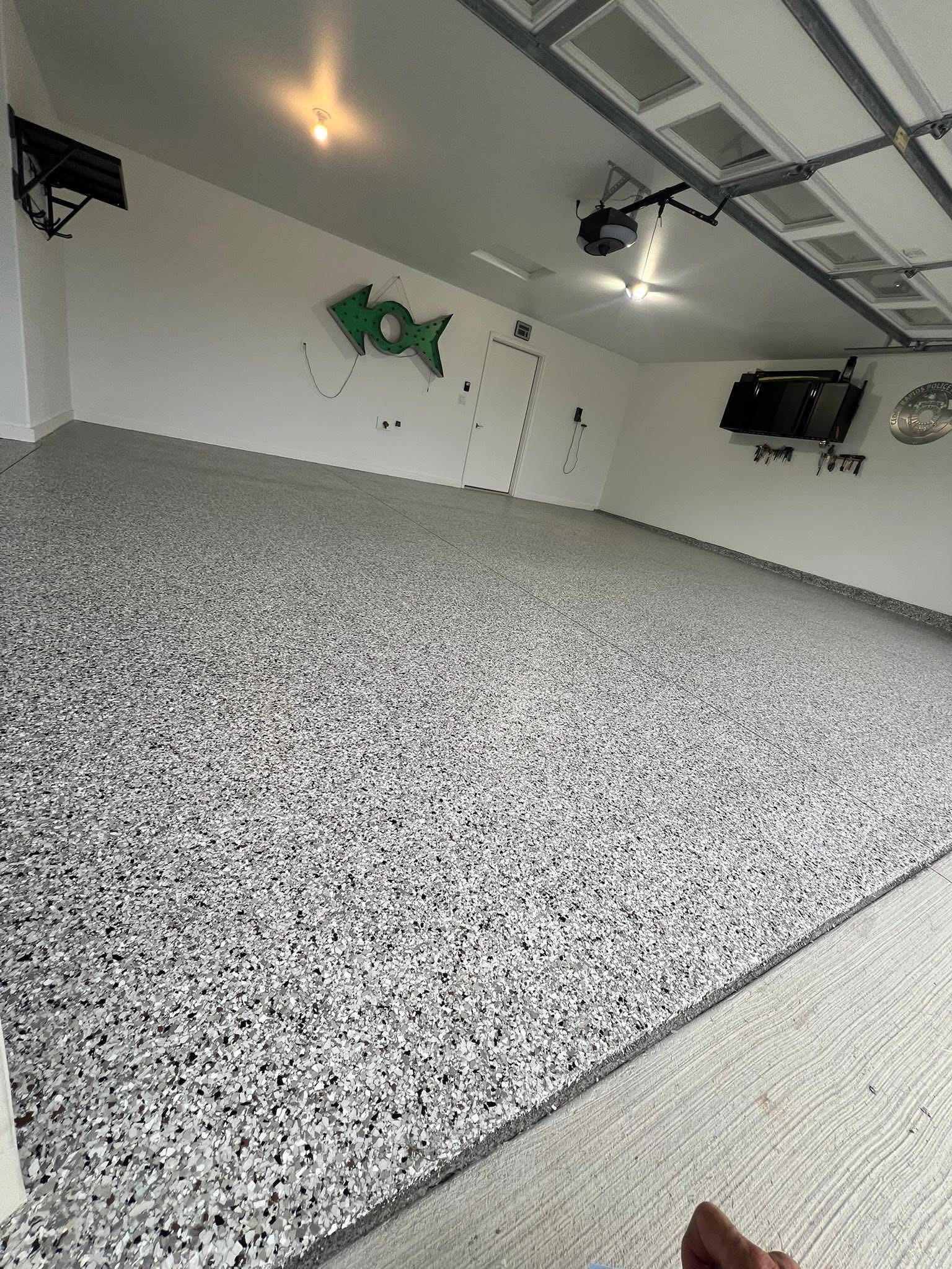 Garage with gray and white speckled epoxy floor, white walls, and a green fish decoration.