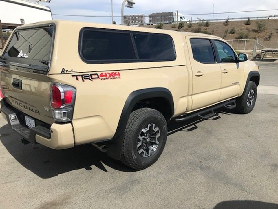 Two people camping by a campfire next to a truck with a rooftop tent under a starry sky.