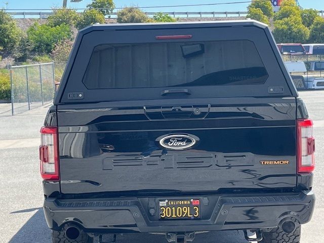 A black Ford Tremor pickup truck with a black camper shell seen from the rear, parked outdoors with a California plate.