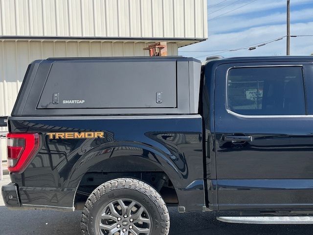 A black Ford Tremor pickup truck with a black GearCap brand utility truck cap installed on the bed.