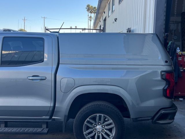 A silver pickup truck parked outdoors, featuring a matching hard-shell camper topper over the truck bed.