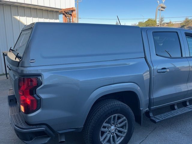 A grey pickup truck viewed from the rear, equipped with a matching grey hard-shell camper topper over the truck bed.