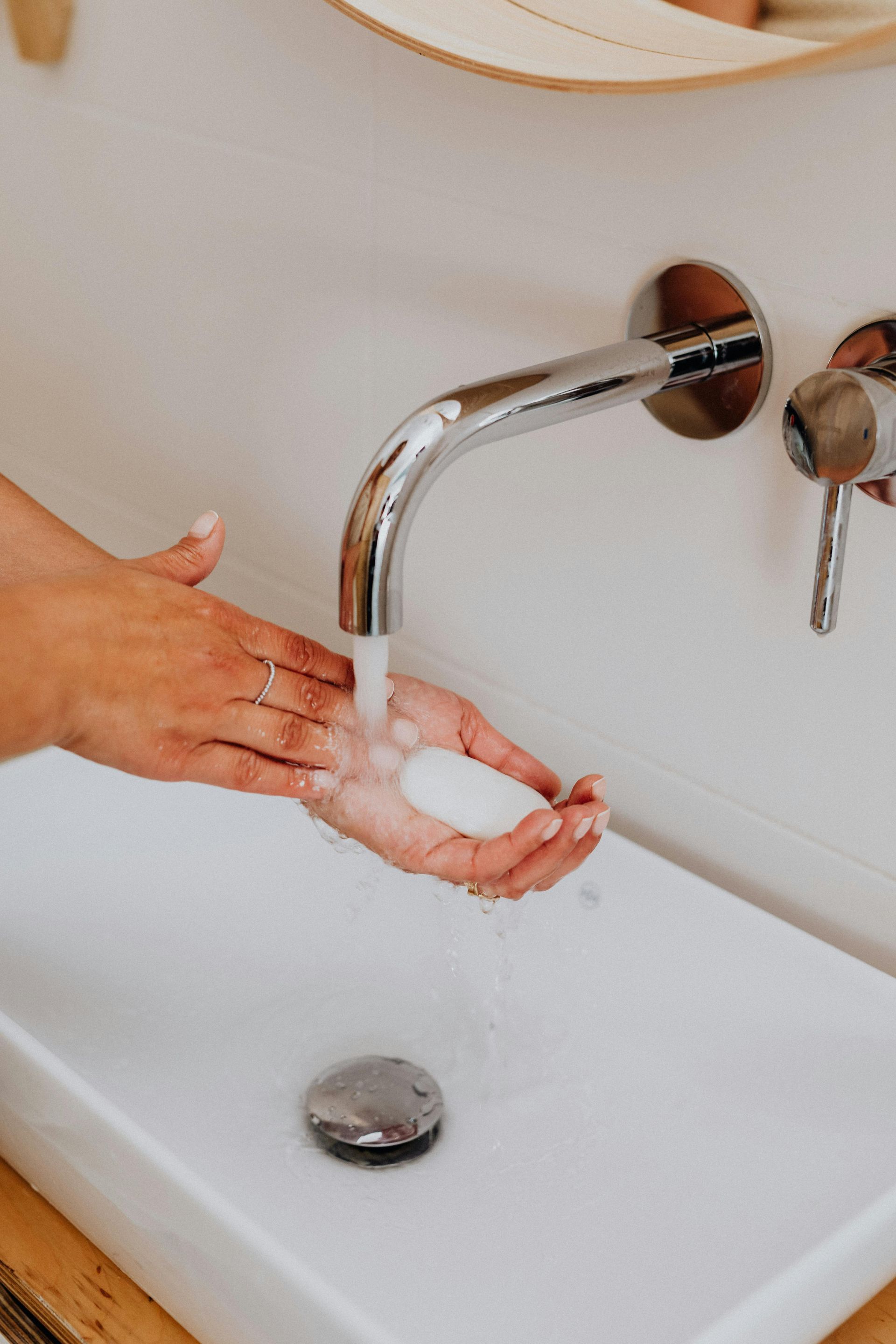 A person is washing their hands in a bathroom sink.