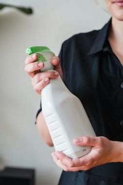 A woman is holding a spray bottle in her hands.