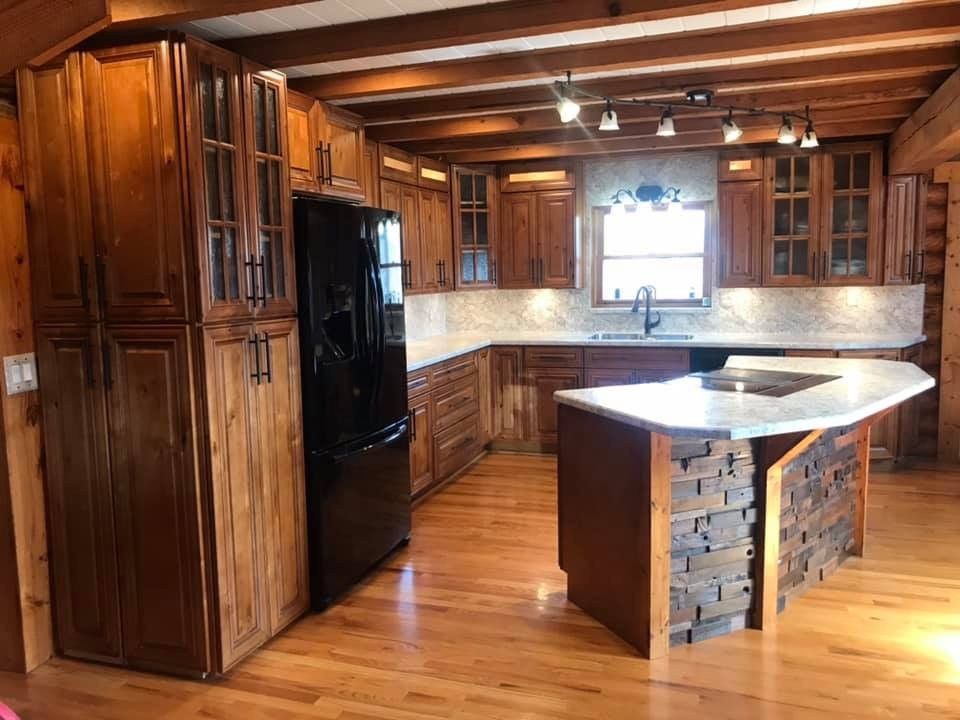 A kitchen with wooden cabinets and a black refrigerator