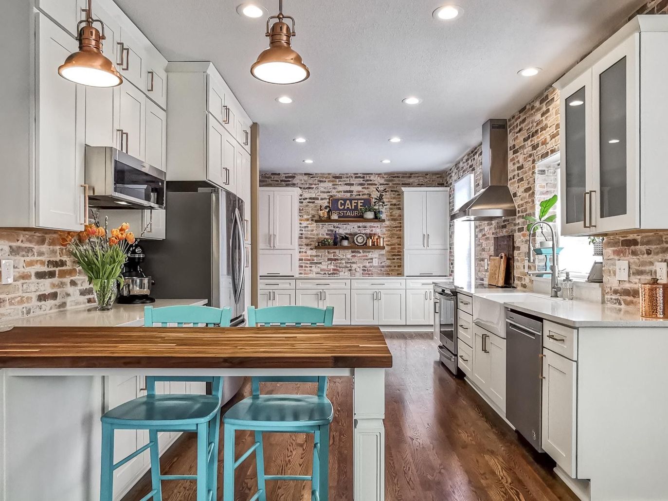 A kitchen with white cabinets , stainless steel appliances , a sink , and a large island.