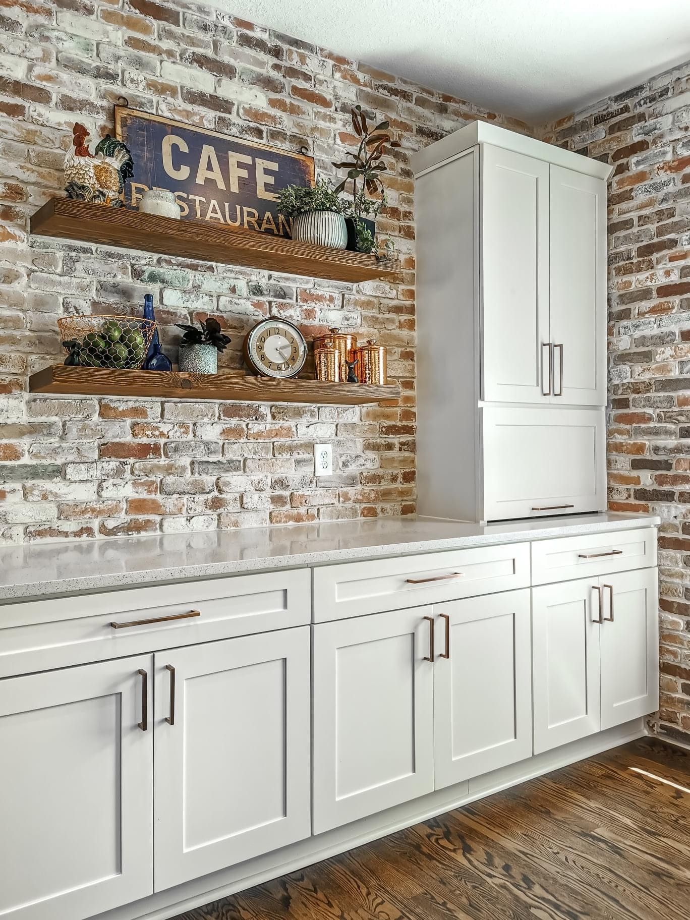 A kitchen with white cabinets and a brick wall.