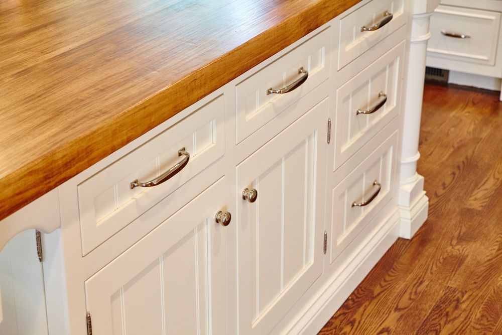 A kitchen with white cabinets and a wooden counter top