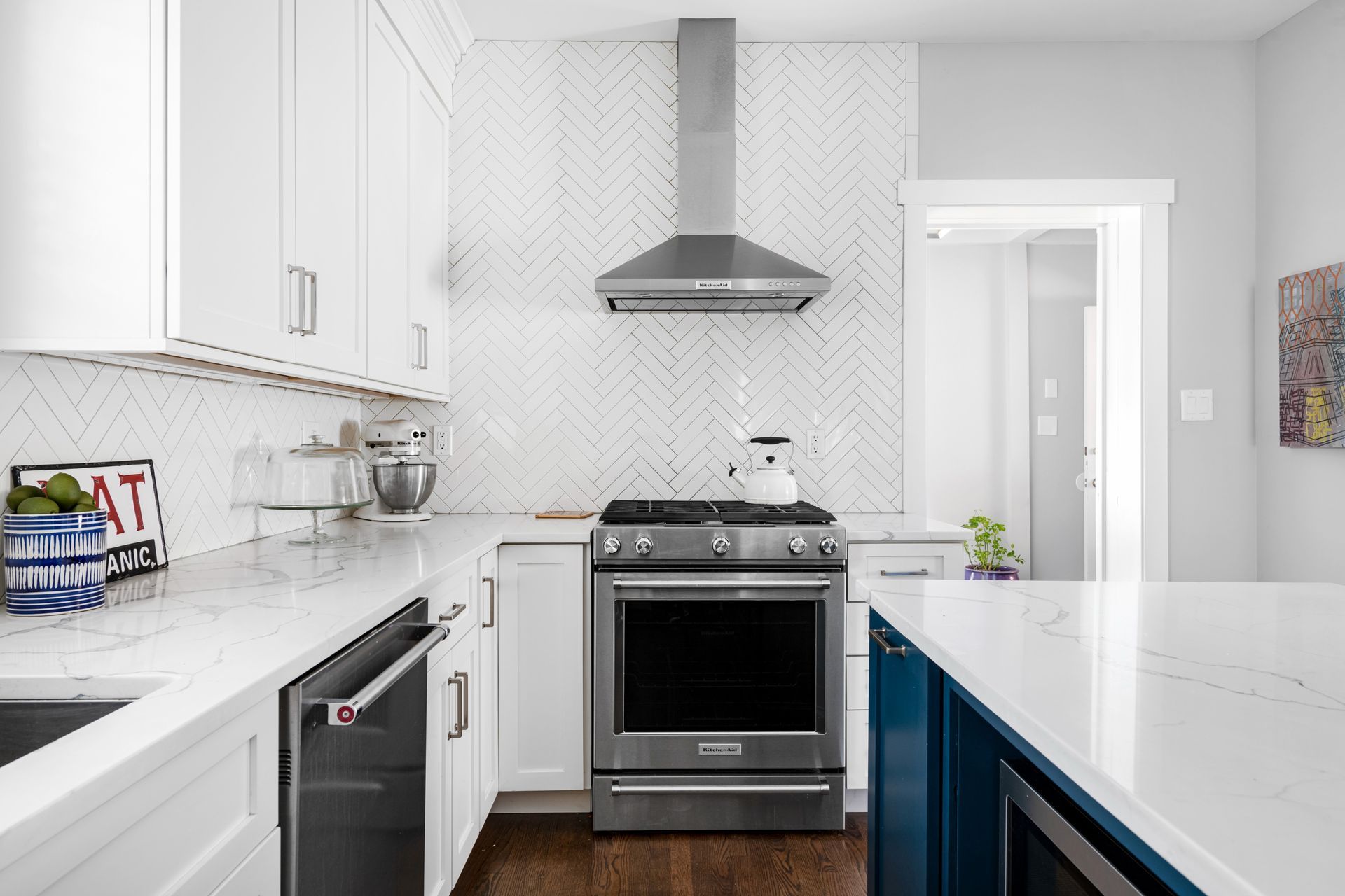 A kitchen with white cabinets , stainless steel appliances , a stove and a dishwasher.