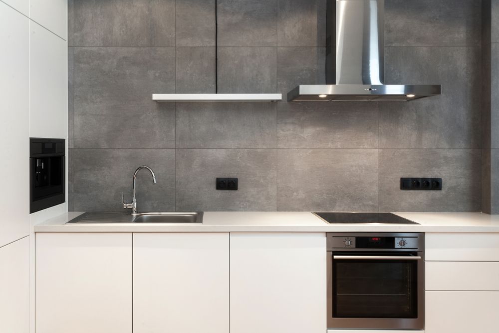 A kitchen with white cabinets , a stove , a sink , and a hood.