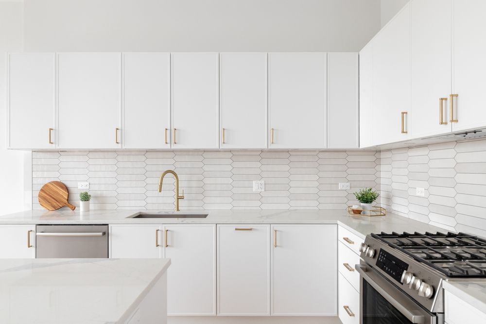 A kitchen with white cabinets , stainless steel appliances , a sink , and a stove.