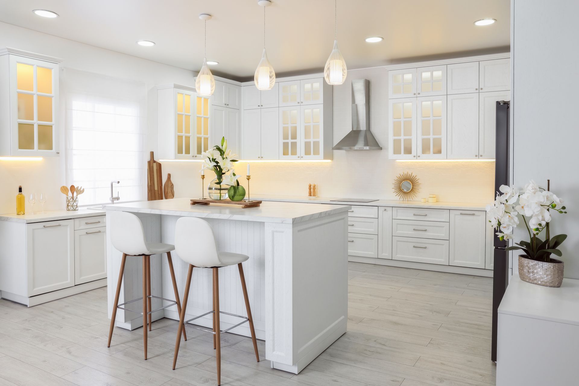 A kitchen with white cabinets and stools and a large island.