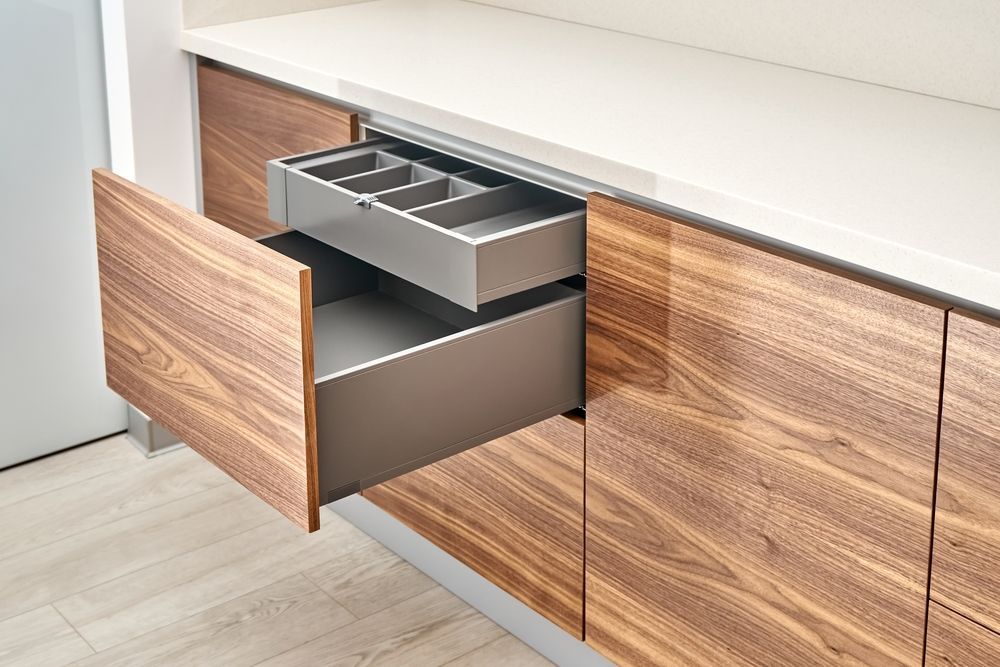 A kitchen with wooden cabinets and a drawer open.