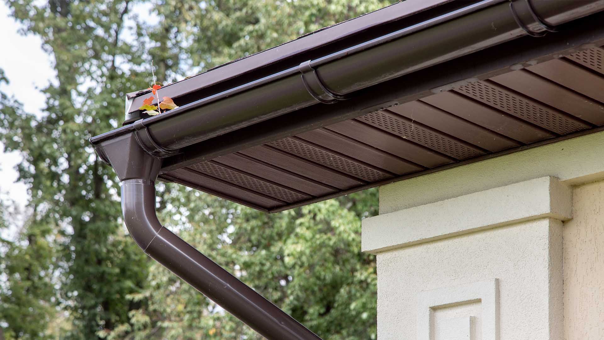 A close up of a gutter on the side of a house.