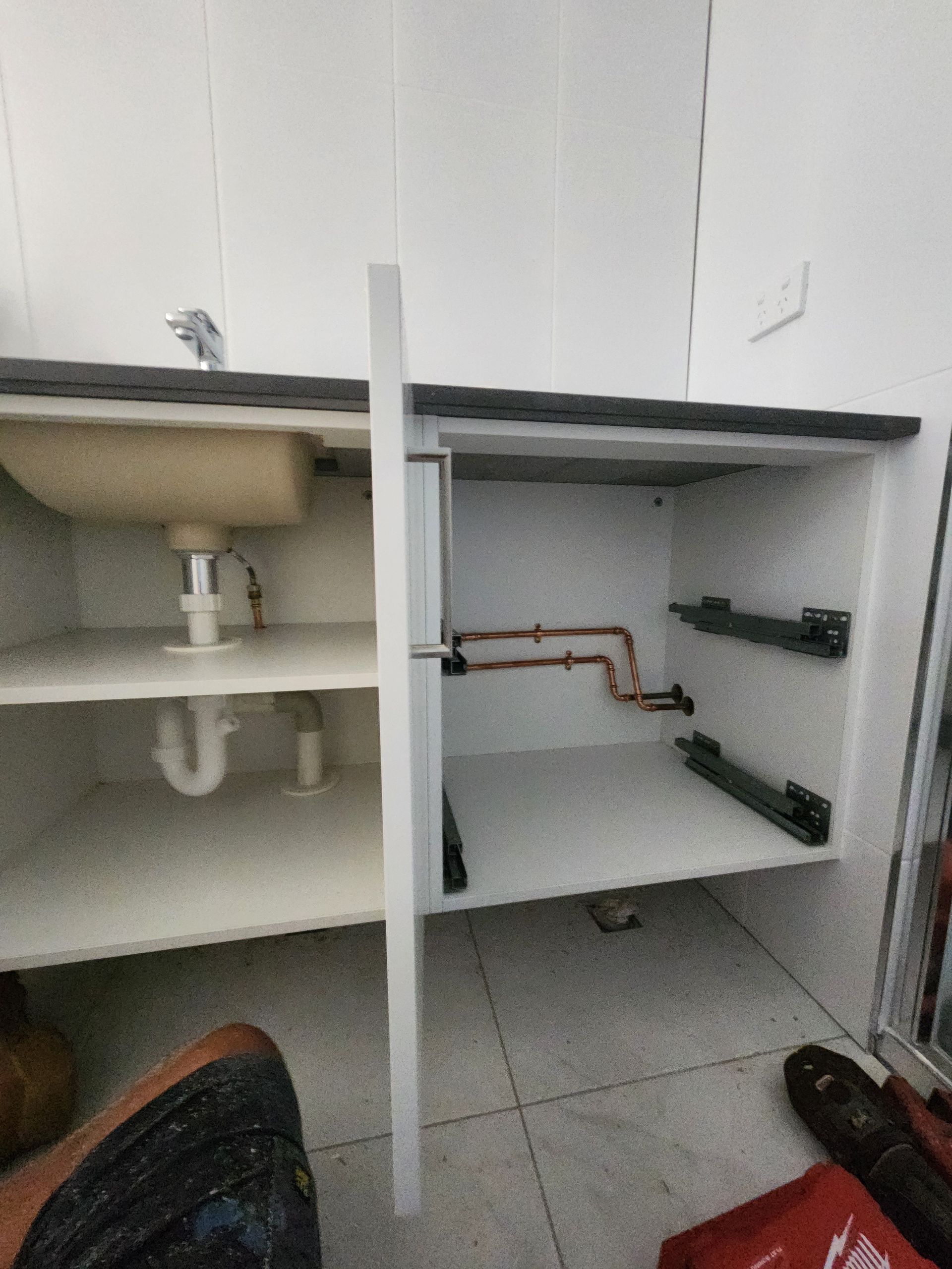 A White Kitchen Cabinet With an Open Door — Kingdom Plumbing Services in Gordonvale, QLD