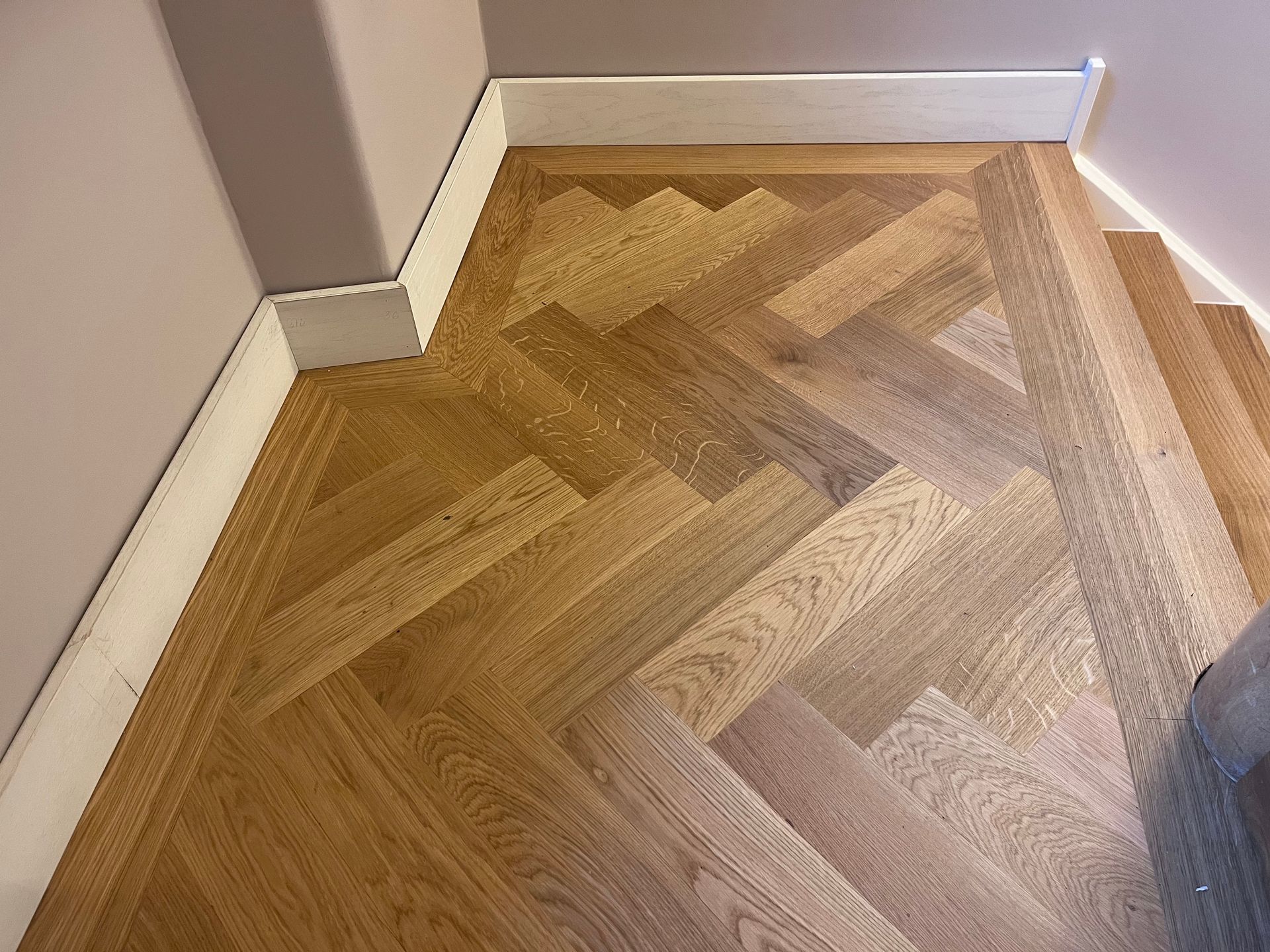 Fischgrät Parkett aus Eiche mit umlaufendem Fries im Treppenhaus