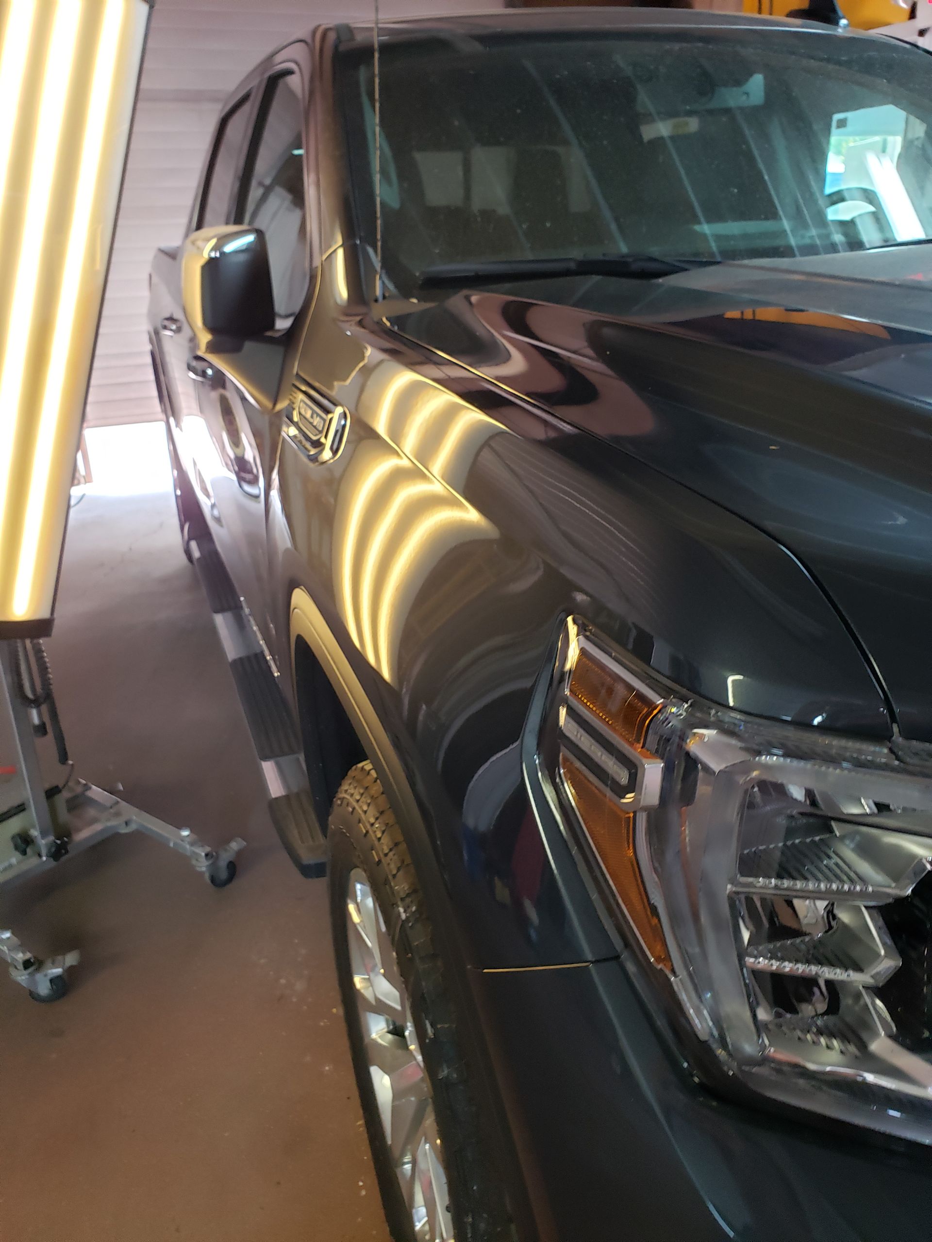 A black truck is parked in a garage next to a pdr board