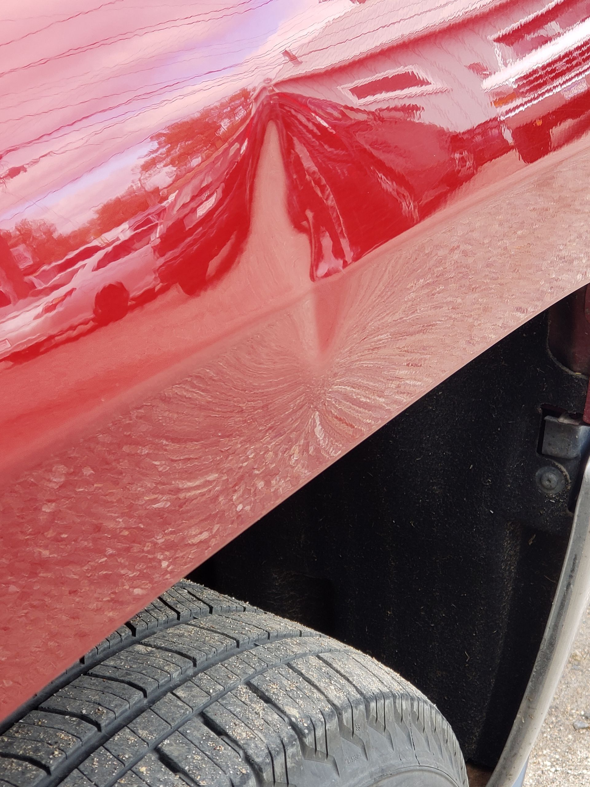 A close up of a red car with a damaged fender