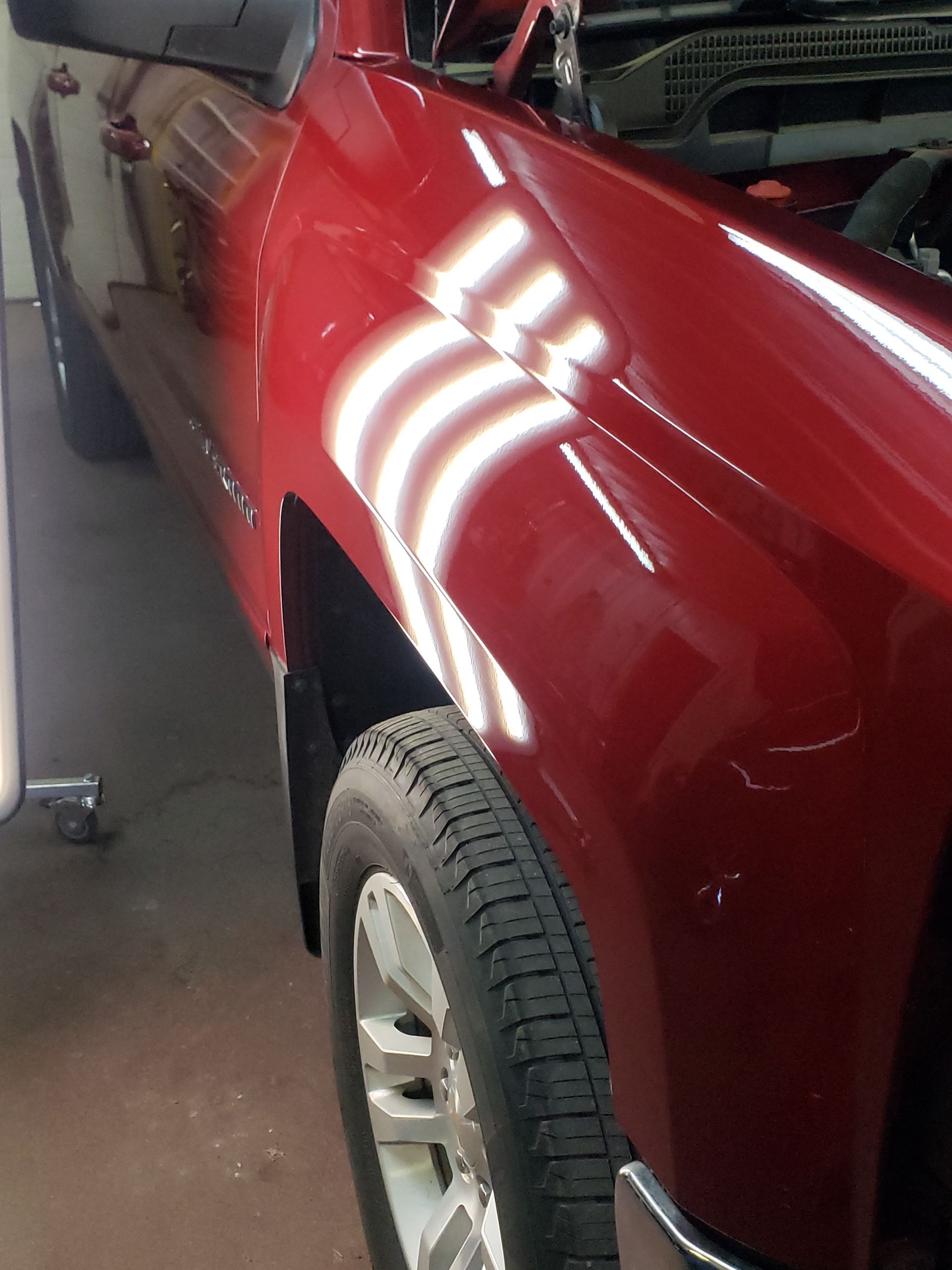 A red truck is parked in a garage with the hood up