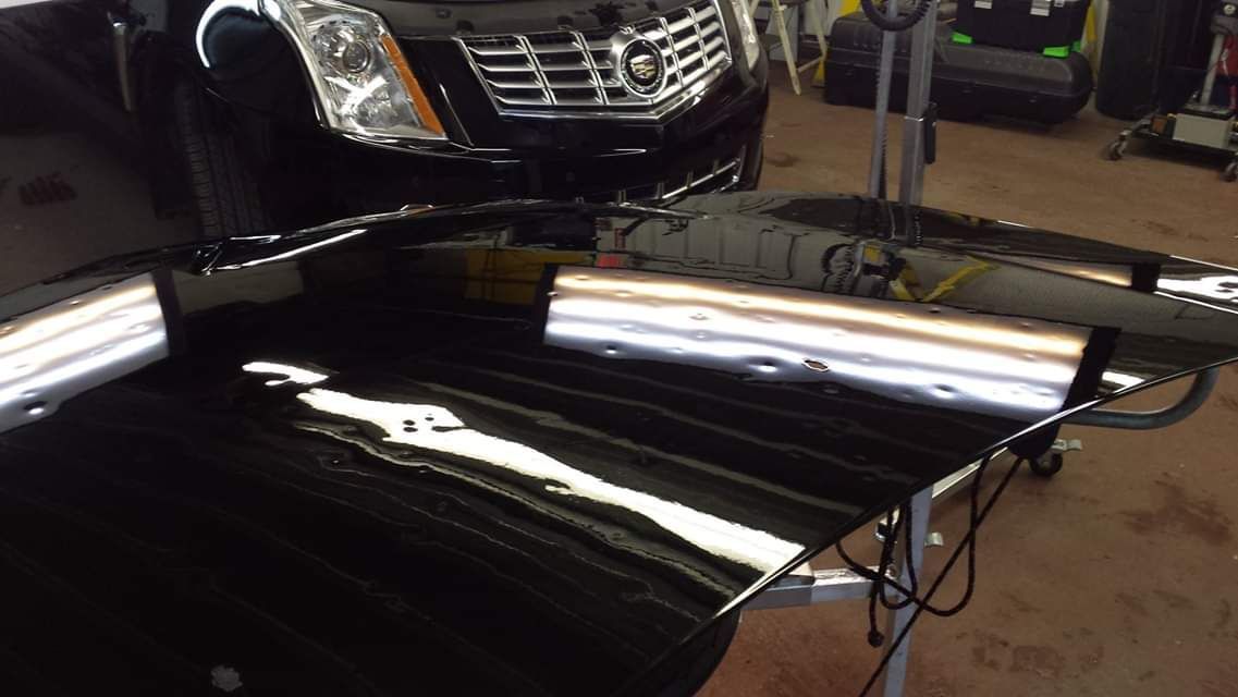 A black car is sitting on a table in a garage.